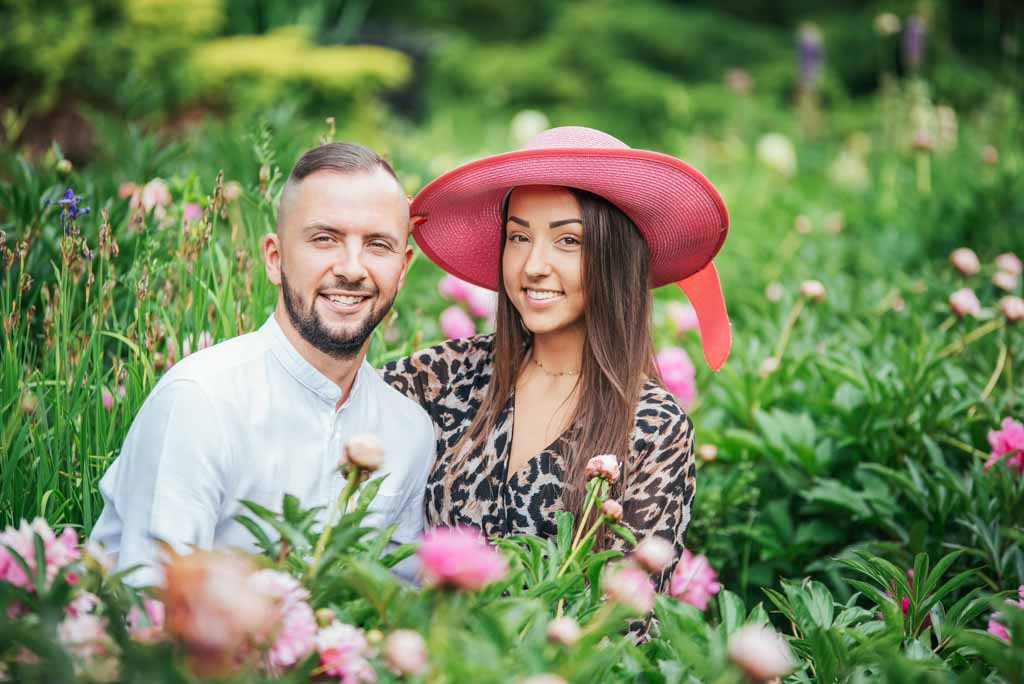 dziewczyna w różowym kapeluszu z chłopakiem wśród kwiatów